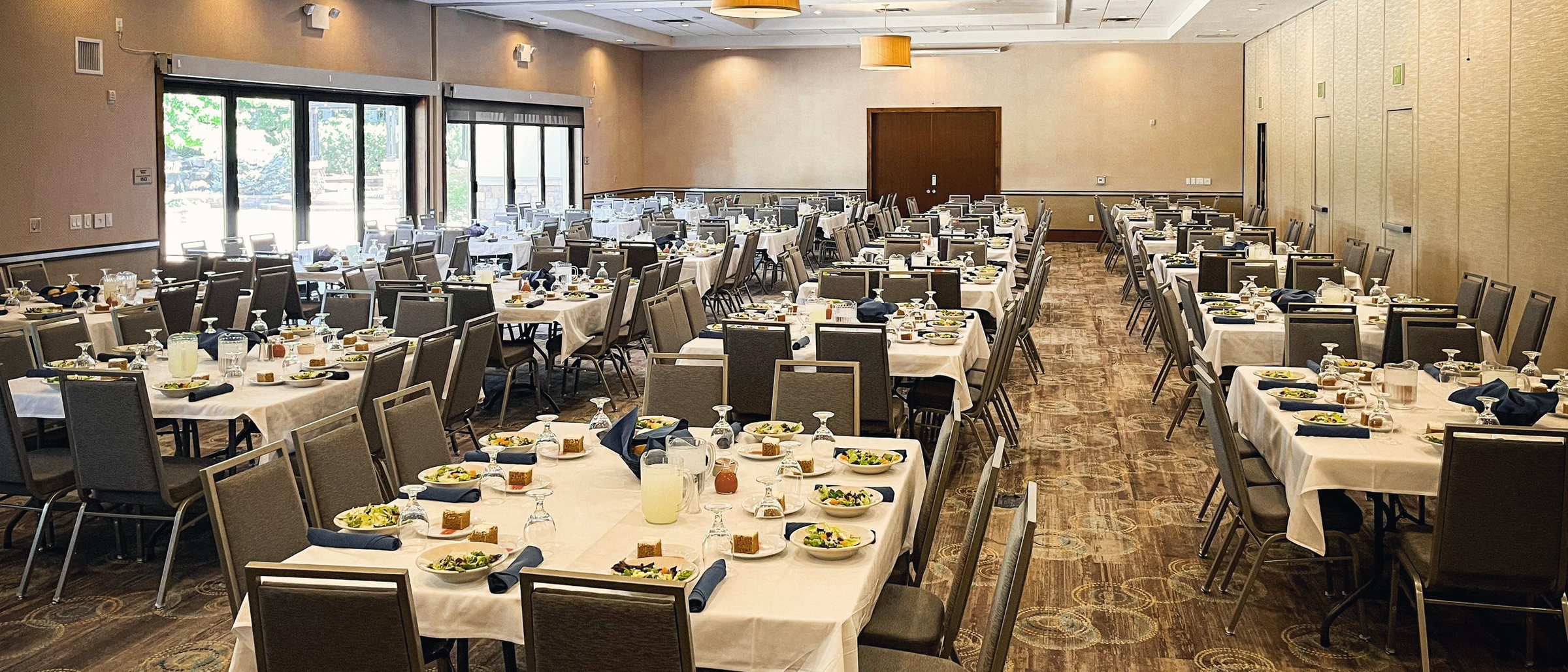 The ballroom set with round tables and gold chairs for a banquet, with elevated ceilings.